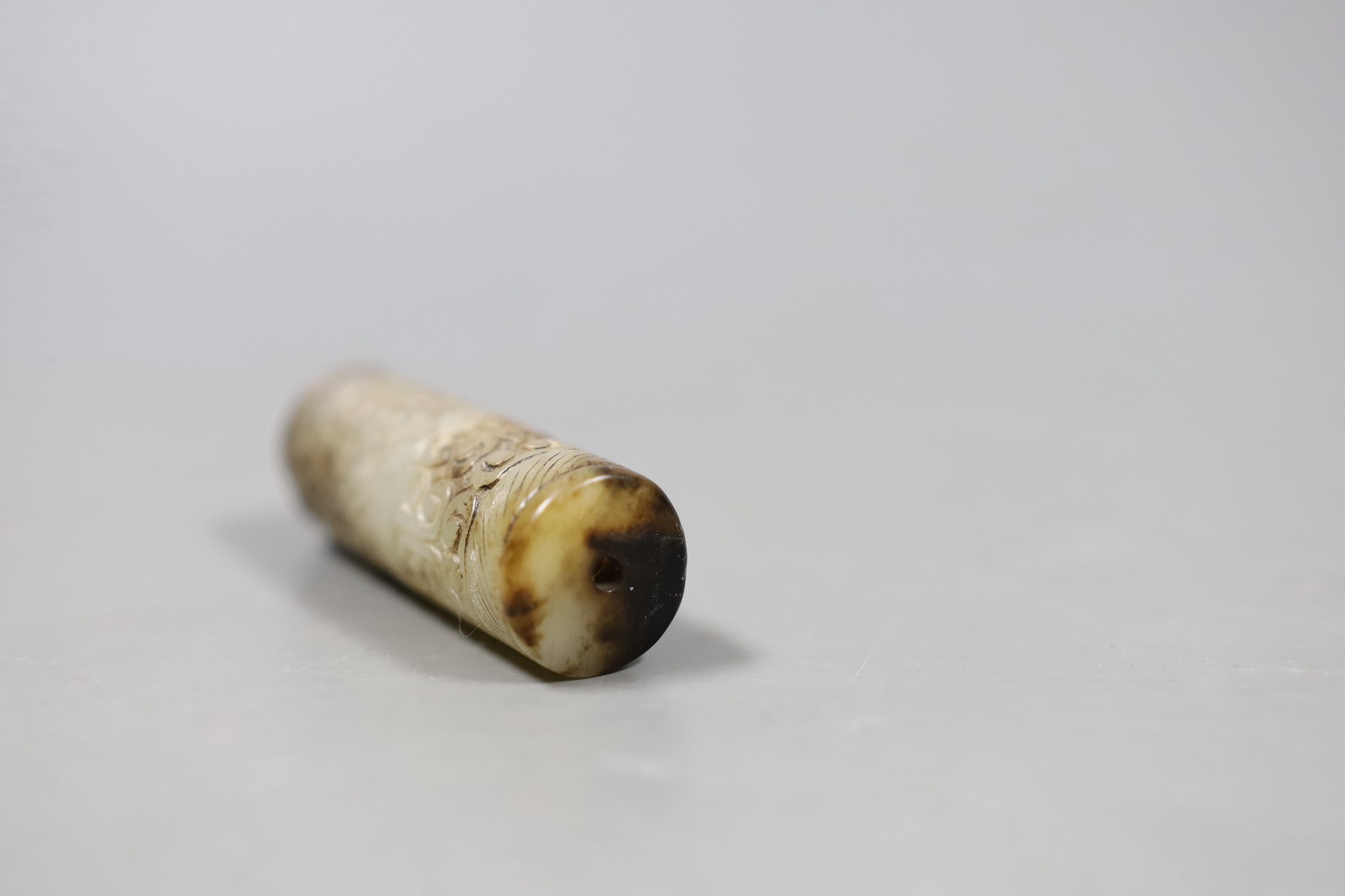 A Chinese archaistic white and black jade cylinder bead, 5.8 cm, boxed and a Chinese archaistic jade large bi disc, 13 cm diameter